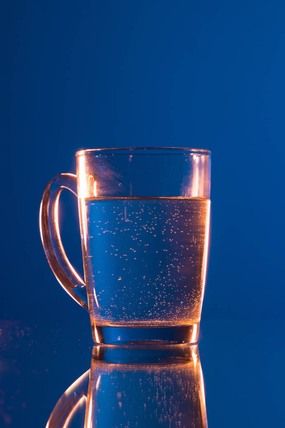Water in glass, on dark blue background - Foto, imagen