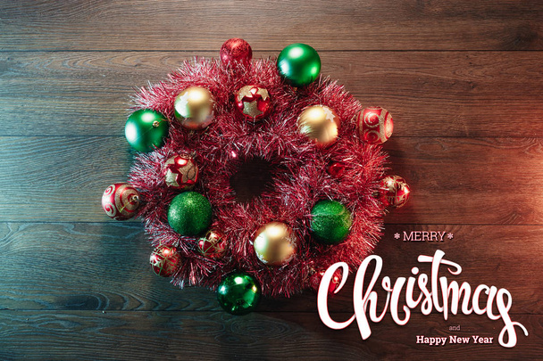 The inscription of Merry Christmas and Happy New Year, a wreath on a wooden brown table. Christmas card, holiday background. Mixed media. - Foto, afbeelding