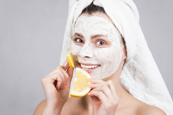 beautiful girl makes fruit cosmetic face mask. Attractive girl with spa mask smiling and holding citrus fruit. Beauty and cosmetic skin care. - Fotó, kép