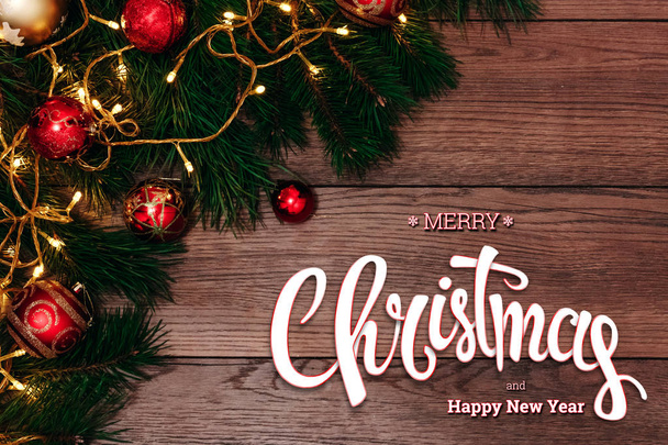The inscription of Merry Christmas and Happy New Year, green spruce and chopping branches on a wooden brown table. Christmas card, holiday background. Mixed media. - Fotoğraf, Görsel