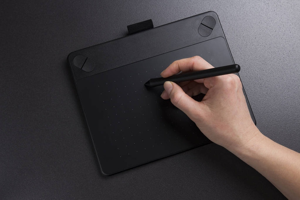 artist draws on graphic tablet. The designer works on graphic tablet closeup. Hand holds pen for paint. - Фото, изображение