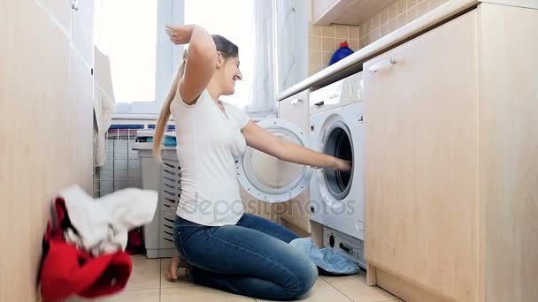 Slow-motion video van gelukkig lachende vrouw nemen kleren uit wasmachine en gooien in de lucht - Video
