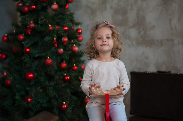 A nice little girl in a gray blank sweatshirt near Christmas tree. Mock up. - 写真・画像