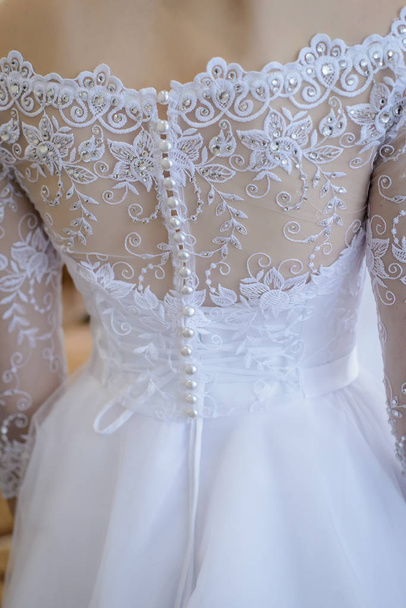 Wedding dress with lots of little white buttons from the back of the bride - Fotoğraf, Görsel