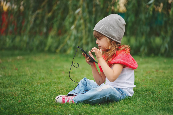 little girl with mobile phone on the grass - Фото, зображення