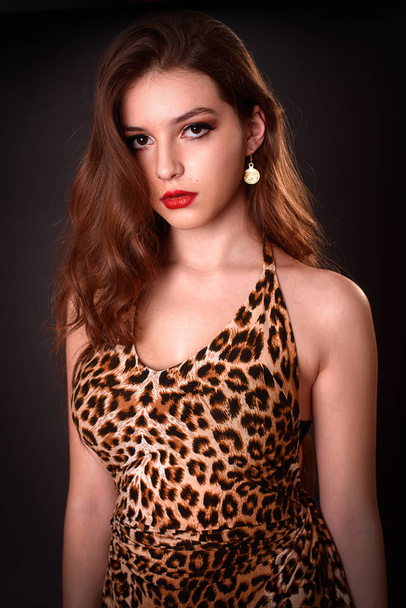 Fashion portrait of young brunette girl in a leopard dress - Фото, зображення