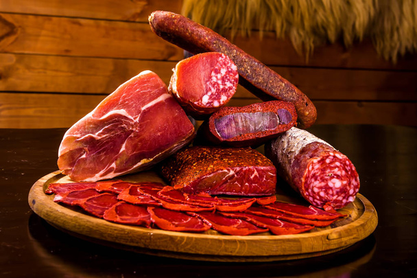 Meat catering platter. Ham, cold-boiled pork, salami, basturma on wooden board - Photo, Image