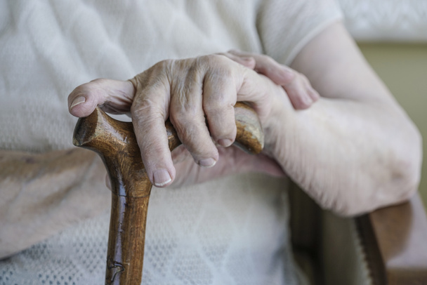closeup wrinkled hand of a senior woman on cane - Photo, Image
