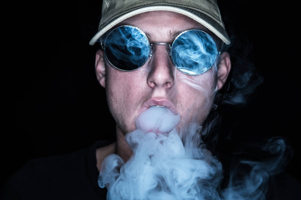 smoking person with cap and sunglasses, smoke out of the mouth - Foto, immagini
