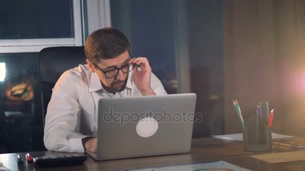 A tired businessman takes off his glasses during work on a laptop. - Filmagem, Vídeo