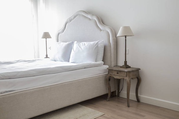 Ένα άνετο διπλό κρεβάτι και φωτιστικό σε κομψό κλασικό υπνοδωμάτιο - Φωτογραφία, εικόνα