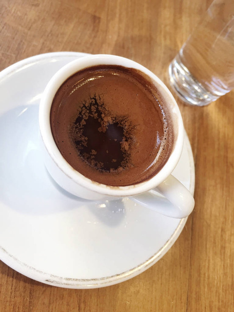 Filiżankę kawy po turecku i szkło wodne na drewnianym stole - Zdjęcie, obraz