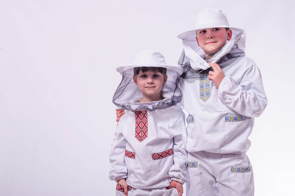 Gyerekek a méhész ruhák pózol stúdió fehér háttér. - Fotó, kép
