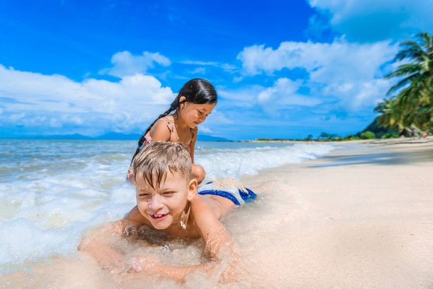 Kaksi lasta pitää hauskaa aurinkoisella trooppisella rannalla
 - Valokuva, kuva