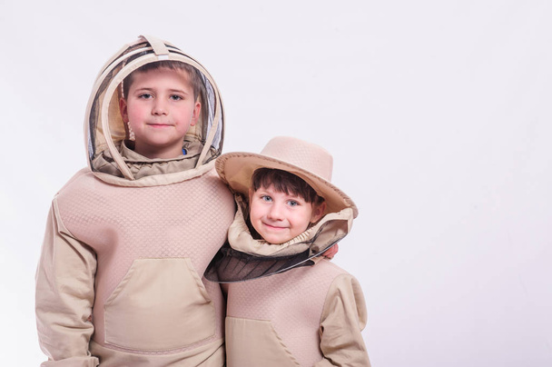 Dzieci w garniturach pszczelarza pozowanie w studio białe tło. - Zdjęcie, obraz