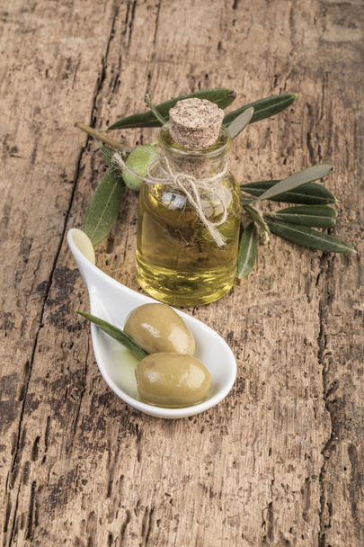 Zelené olivy a olivový olej na dřevěný stůl - Fotografie, Obrázek