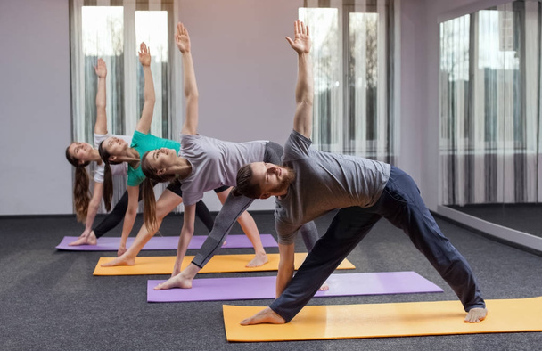 Drei schöne Mädchen und ein Mann machen Yoga im Zentrum von Yoga und Wellness. das Konzept eines gesunden Lebensstils. - Foto, Bild