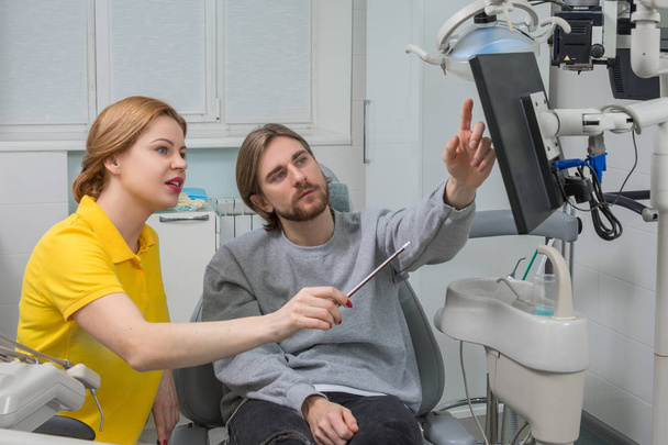 Dentysta pokazuje RTG pacjenta. Opieka stomatologiczna koncepcja. Dental kontroli nadaje się piękny człowiek otoczony dentysta - Zdjęcie, obraz