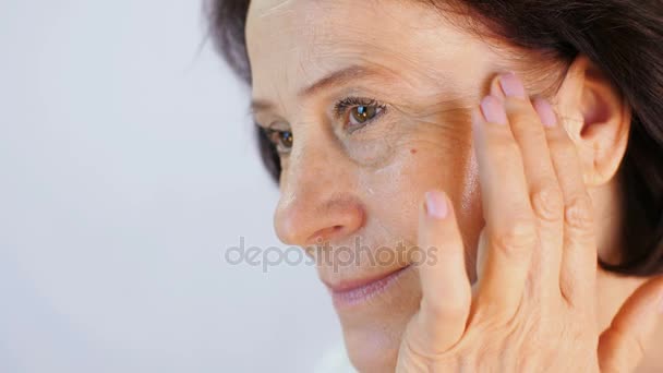 Mature woman applying cream - Filmati, video