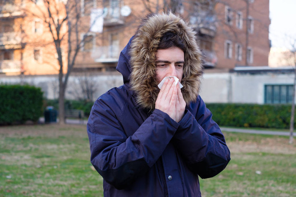 Hombre enfermo estornudando en el pañuelo durante la estación fría
 - Foto, imagen