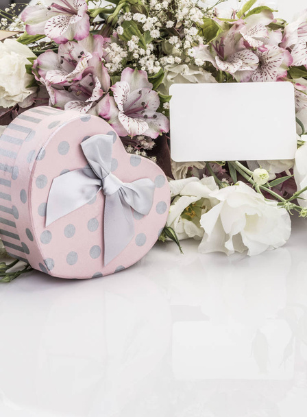 Caja de regalo en forma de corazón y flores con una etiqueta con su nombre
 - Foto, imagen