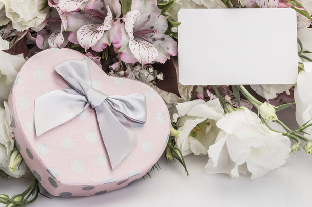 Caja de regalo en forma de corazón y flores con una etiqueta con su nombre
 - Foto, imagen