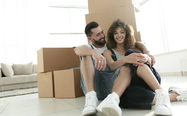 married couple sitting near cardboard boxes in a new apartment - Photo, Image