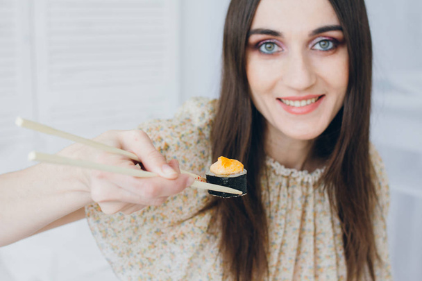 Young brunette woman eating sushi - Fotó, kép