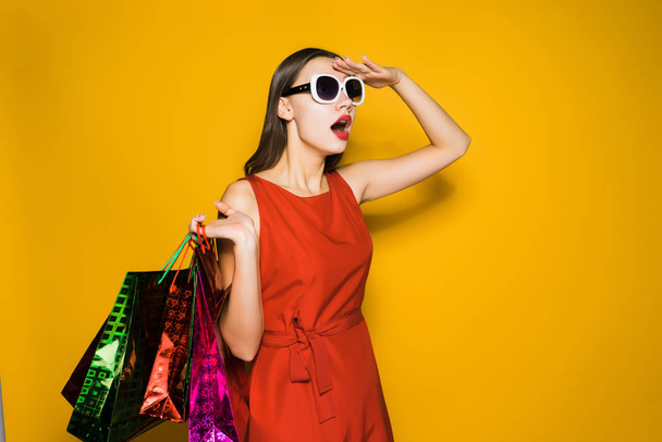 a young beautiful girl in a red dress and sunglasses saw big discounts - Φωτογραφία, εικόνα