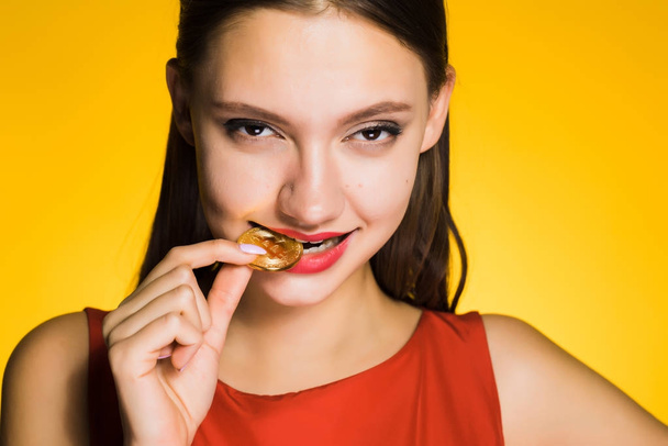 confident young girl tries gold bitcoin to taste, thinks about crypto currency - Fotoğraf, Görsel