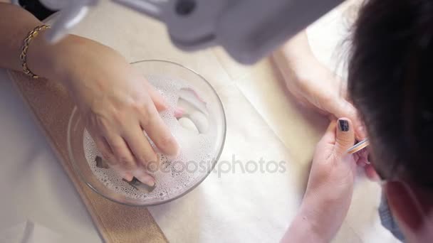 Salón de belleza manicura. manicurista hace el procedimiento para el cuidado de las uñas. procedimiento de hidratación de uñas, la mano yacía en el baño con agua. Primer plano
. - Imágenes, Vídeo