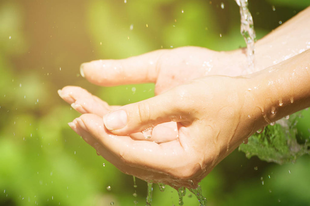 Woman washing hand outdoors. Natural drinking water in the palm. - Photo, Image
