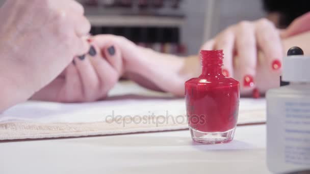 Manicure. Taking a dip from manicure bottle on foreground. Master applies varnish drawing on nails gel in spa . Closeup finger nail care by specialist in beauty salon. - Footage, Video