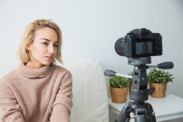Blogging-Konzept. junge Bloggerin neben der Videokamera zu Hause. junge Frau nimmt Vlog auf ihrem Videokanal auf. - Foto, Bild
