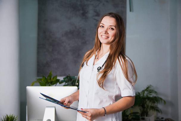 Πορτρέτο του ένα νεαρό επαγγελματική γυναίκα γιατρό χαμογελώντας στην κλινική. Κοντινό πλάνο του μια ουσία της ιατρικής στο νοσοκομείο - Φωτογραφία, εικόνα
