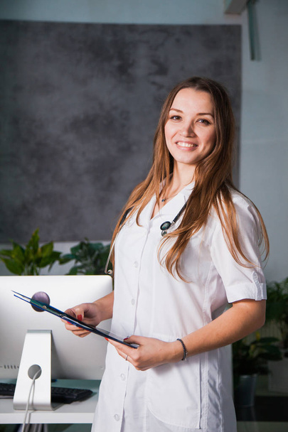 Портрет молодой профессиональной женщины-врача, улыбающейся в клинике. Крупный план лекарств в больнице
 - Фото, изображение