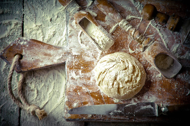 Testo con harina sobre un fondo viejo en una composición con accesorios de cocina
 - Foto, imagen