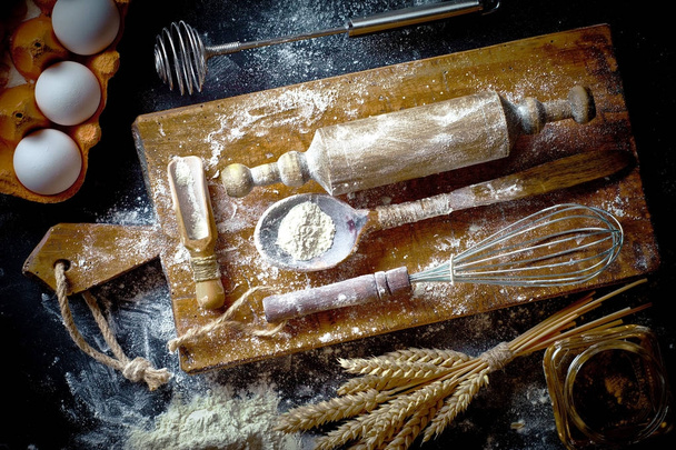 Massa com farinha em um velho fundo em uma composição com acessórios de cozinha
 - Foto, Imagem