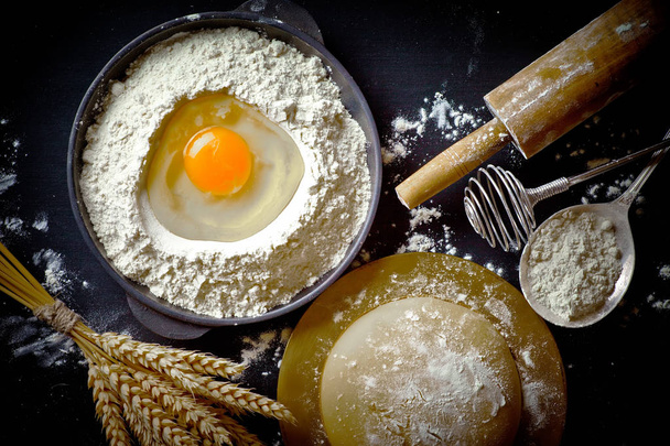 Ζύμη με το αλεύρι σε μια παλιά φόντο σε μια σύνθεση με αξεσουάρ κουζίνας - Φωτογραφία, εικόνα