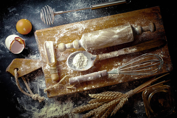 Dough with flour on an old background in a composition with kitchen accessories - Zdjęcie, obraz