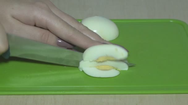 Die Eier mit einem Messer schneiden und gekochte Eier mit einem Küchenmesser zerkleinern. Salate zu Hause kochen - Filmmaterial, Video