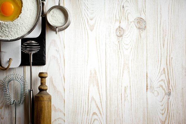 Тесто с мукой на старом фоне в композиции с кухонными принадлежностями
 - Фото, изображение