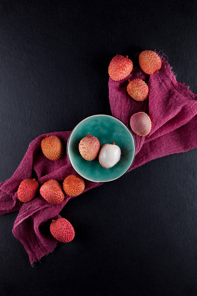 ripe, vermilion exotic lichees decorated on a slate plate kitchen table background with napkin - Foto, Imagen