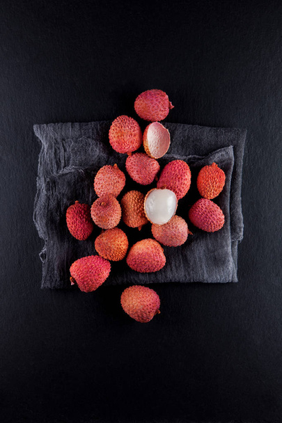 ripe, vermilion exotic lichees decorated on a slate plate kitchen table background with napkin - Photo, Image
