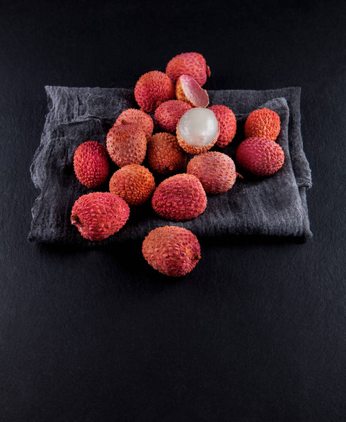 ripe, vermilion exotic lichees decorated on a slate plate kitchen table background with napkin - Foto, Imagen