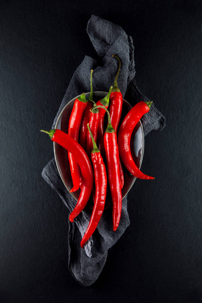 red hot chilli peppers decorated on slate plate kitchen table can be used as background - Fotoğraf, Görsel