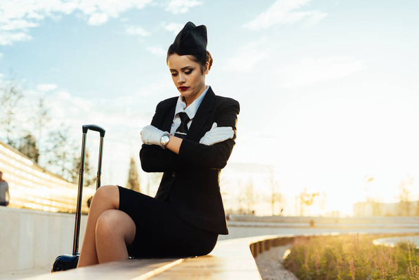 confident slender woman stewardess in uniform sits in the park, waiting for the flight, froze - Foto, Imagem