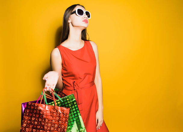 an attractive stylish girl in a red dress and sunglasses went shopping - Foto, Imagem