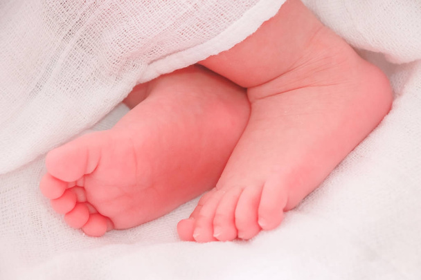 Közelről baba láb fehér ágyban alszik - Fotó, kép