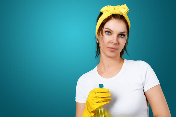 A girl, a cleaning lady with a cleanser, wearing gloves and a rag on a blue background. The concept of cleanliness in the house, cleaning of premises, cleanliness. - 写真・画像